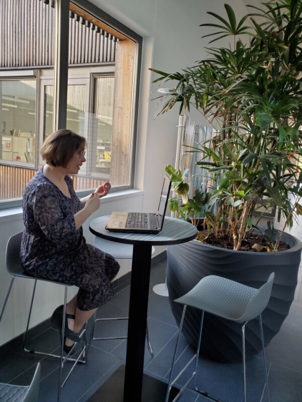 Cette photo montre Cécile GUILLARD, coach santé et bien - être assise face à son ordinateur. Elle communique avec son client en visio. L'image montre une coach dynamique et souriante, à l'écoute de son client particuliers hommes femmes soignants aidants patients